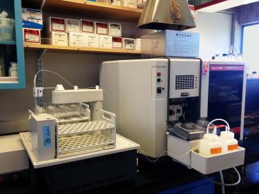 A cream colored boxy scientific instrument on a desk in a lab